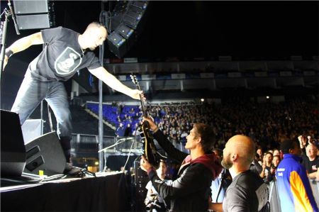 Alter Bridge's Mark Tremonti hands a lucky fan his guitar following their concert at the O2 Arena in London.
